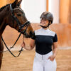 A lady standing and smiling with a horse